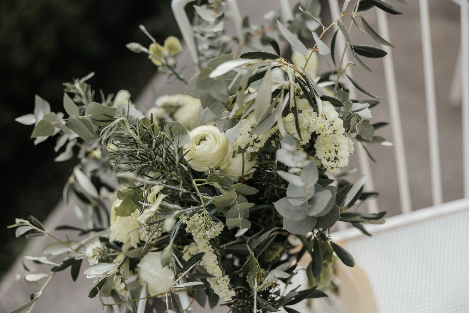 An elegant wedding bouquet featuring white flowers and eucalyptus leaves against a light background.
