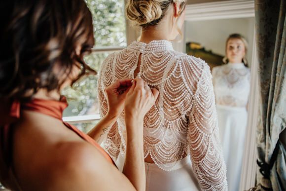 Feine Spitzen­details des Brautkleids im natürlichen Fensterlicht – zarte Eleganz beim heiraten im Morrhof.