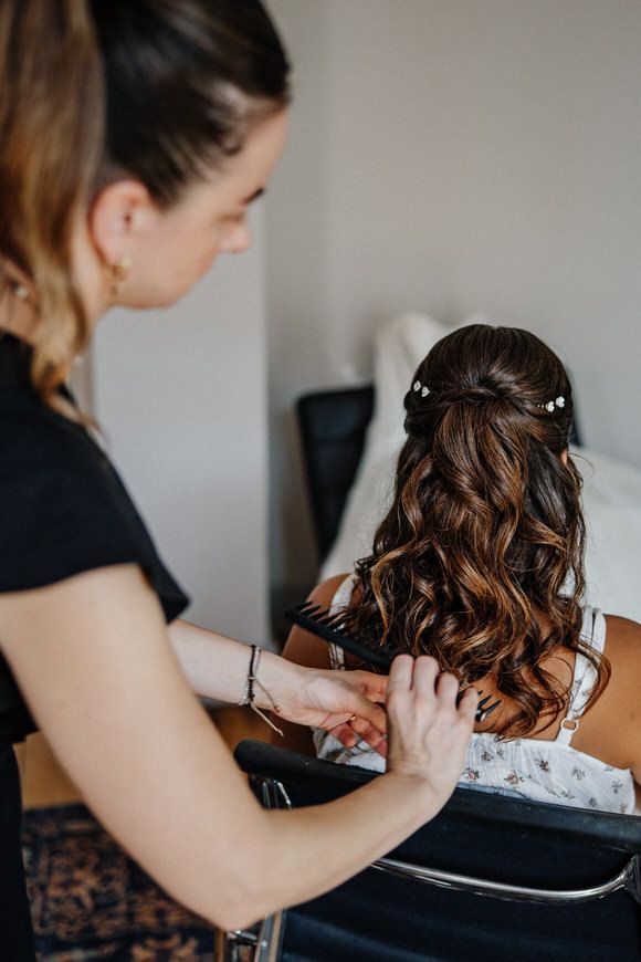 Hochzeitsfotograf Boudier & Koeller – Hairstylistin stylt lockiges braunes Haar während eines Beauty-Termins.