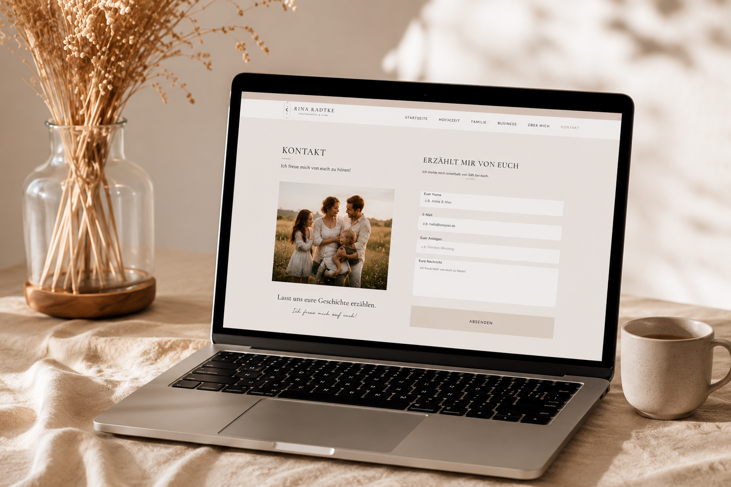 Laptop displaying an elegant photography website with a contact form, styled on a neutral linen desk with dried flowers and coffee.