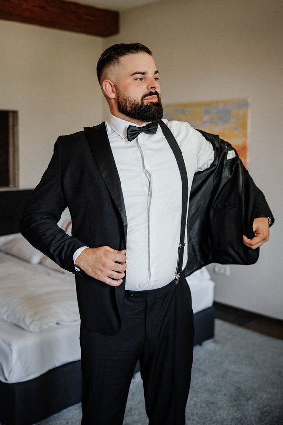Hochzeitsfotograf Boudier & Koeller – Person im schwarzen Smokingjackett und weißem Hemd richtet formelle Kleidung.