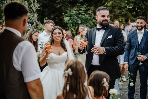 Hochzeitsfotograf Boudier & Koeller – Gäste stoßen draußen bei sommerlicher Gartenhochzeit an.