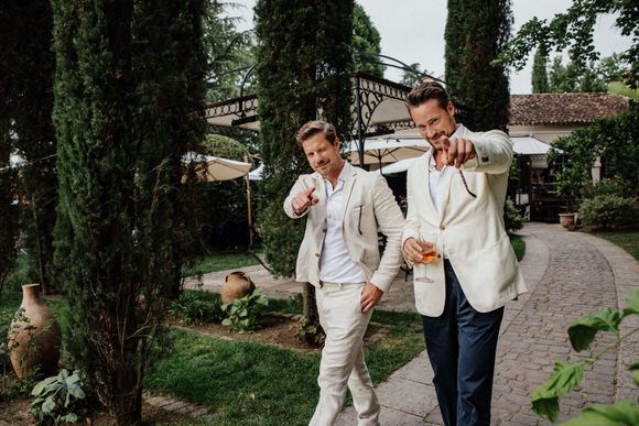 Gruppe von Hochzeitsgästen spaziert plaudernd entlang eines Weges mit Zypressen – romantisch heiraten im Morrhof.