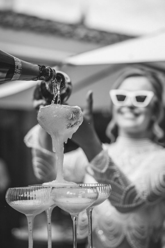 Schwarz-Weiß-Bild von Champagner, der in gestapelte Gläser gegossen wird – stilvoll heiraten im Morrhof.