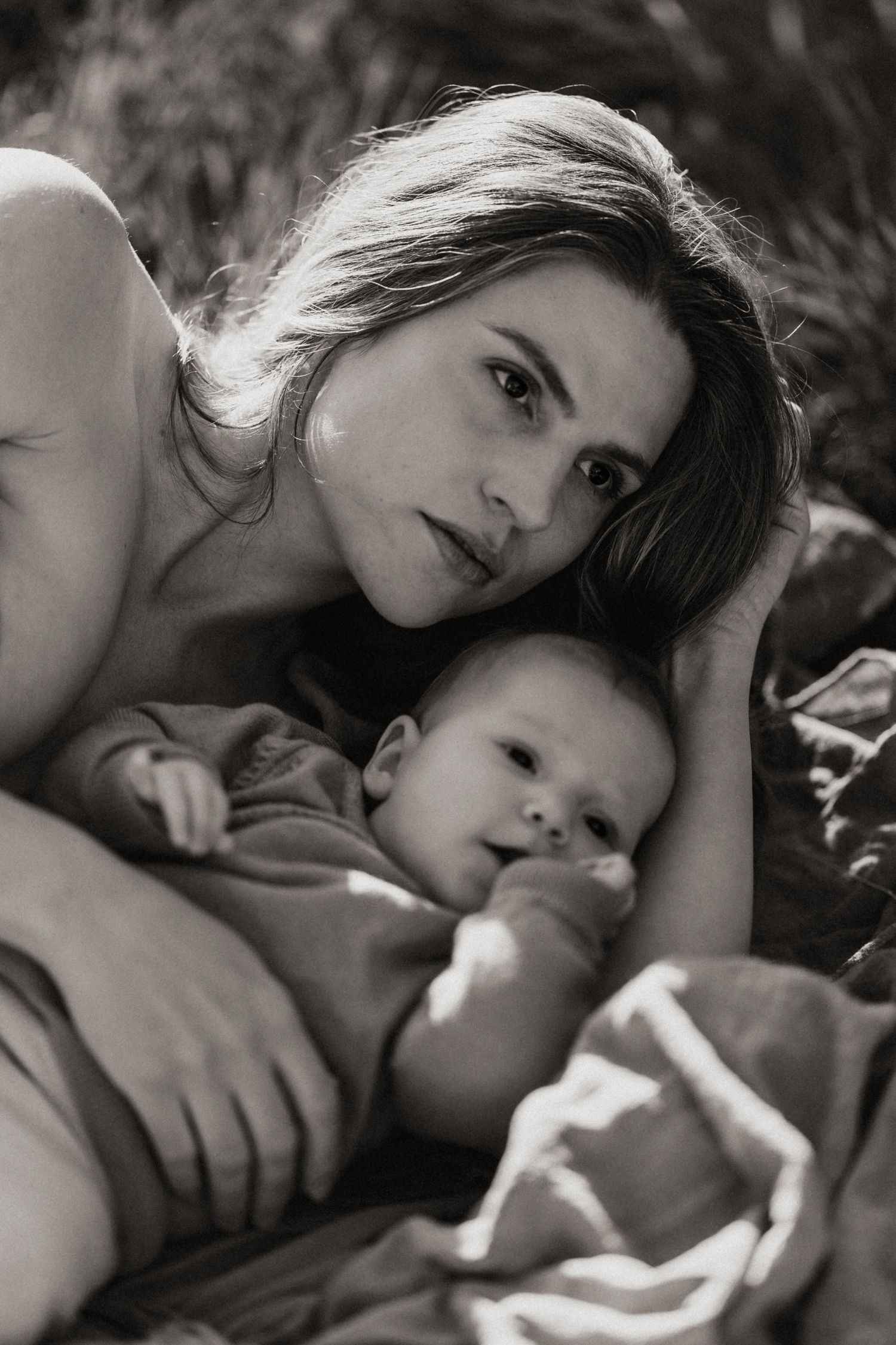 Black and white portrait of a mother and baby lying together in an intimate moment.
