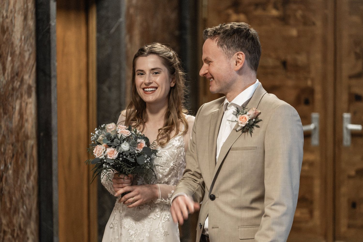 Romantic wedding couple in a rustic barn setting with warm lighting and floral bouquet.