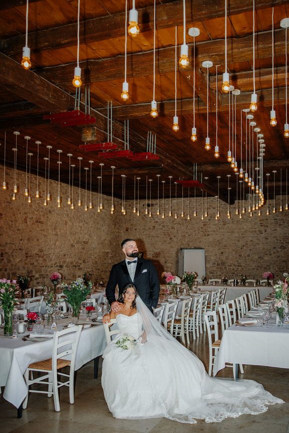 Hochzeitsfotograf Boudier & Koeller – Hochzeitslocation mit rustikalen Steinwänden, Lichterketten und weiß gedeckten Tischen.