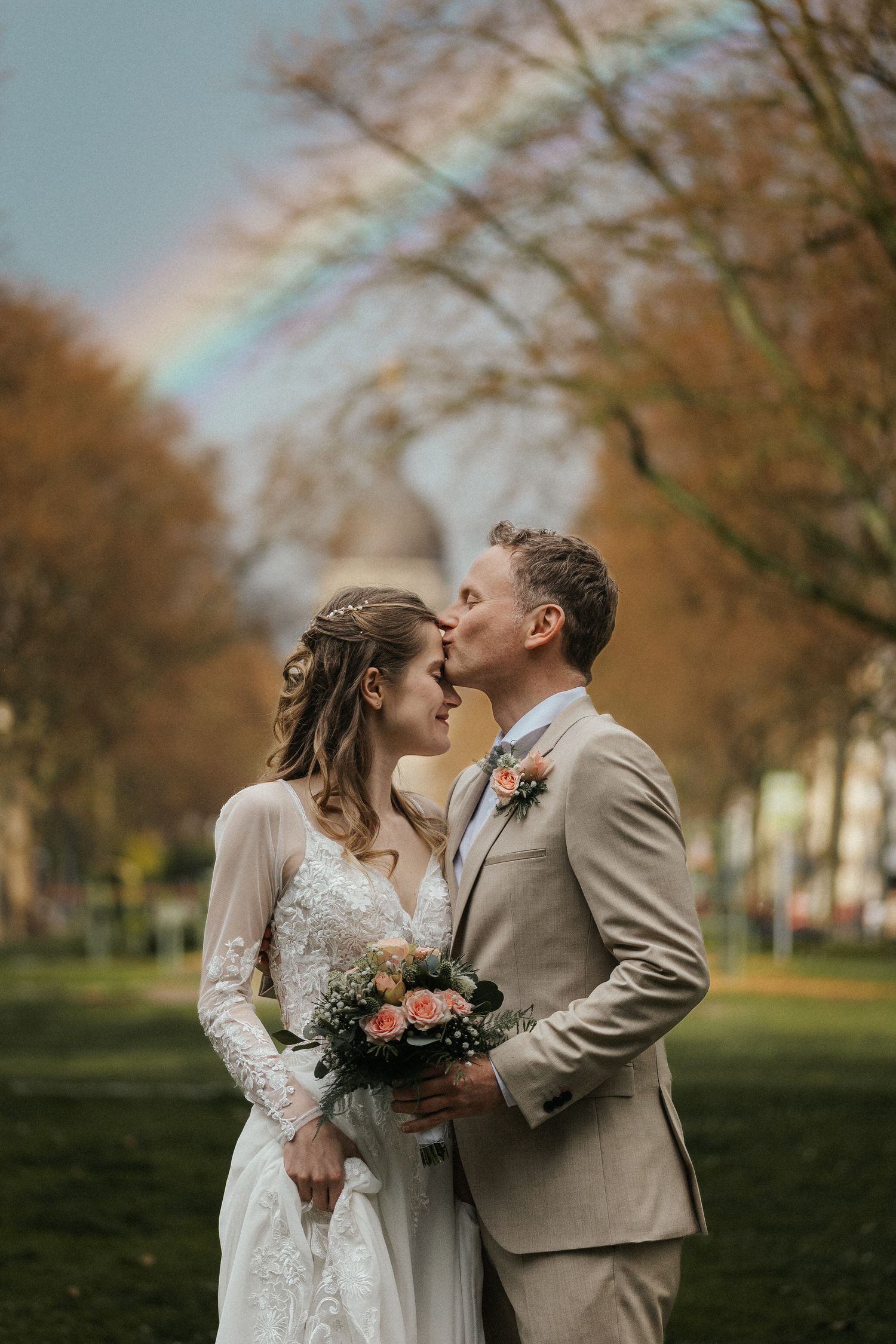 Newlyweds share tender moments in an autumn park setting with warm lighting and fall foliage.
