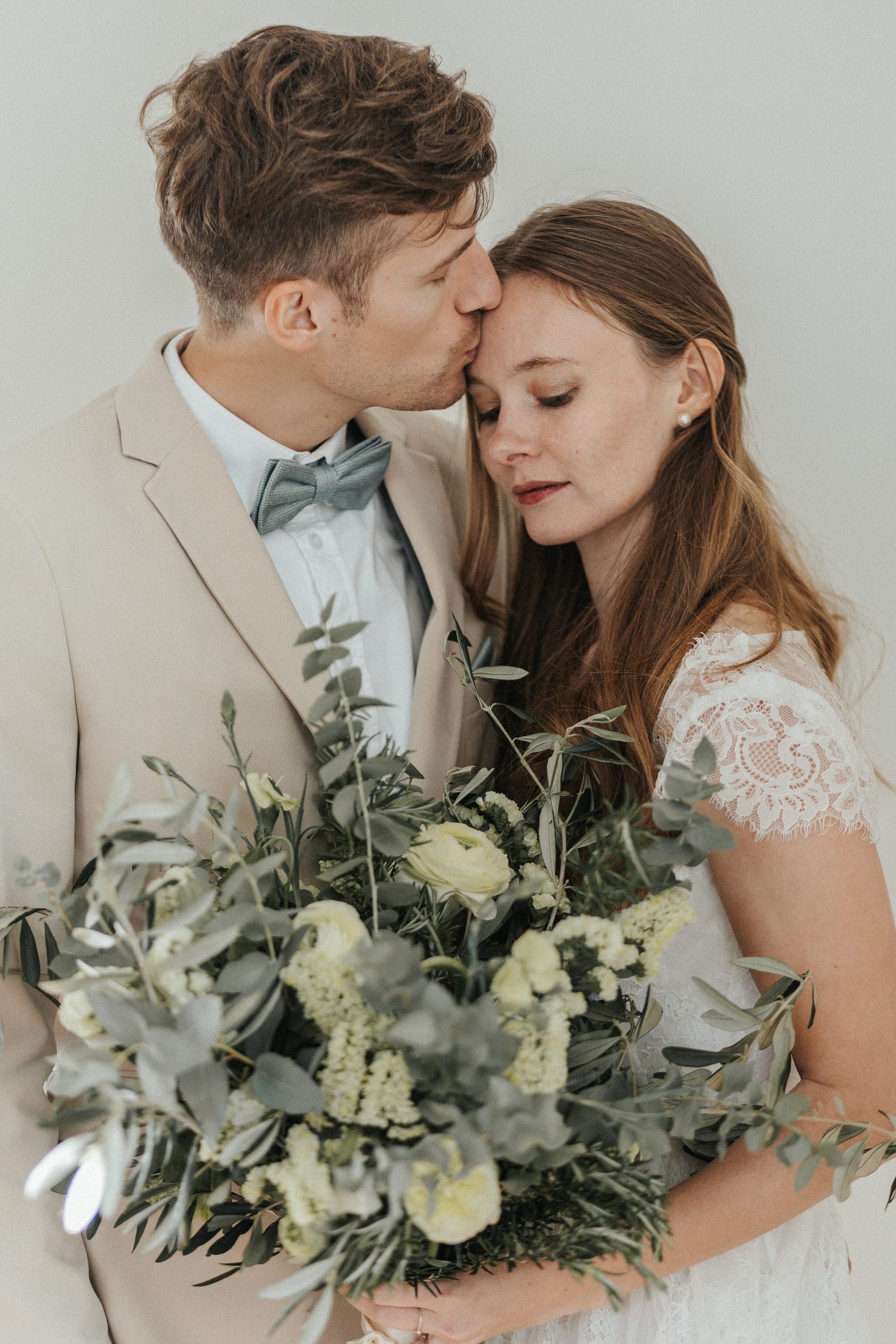 Romantic wedding portrait with eucalyptus and white floral bouquet against white background.
