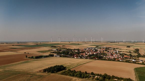 Hochzeitsfotograf Boudier & Koeller – Luftaufnahme einer ländlichen Landschaft mit Feldern und kleinem Dorf in der Ferne.