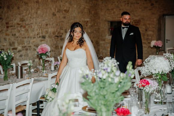 Hochzeitsfotograf Boudier & Koeller – Rustikale Hochzeits-Tafel mit rosa Blumen und Grün vor Ziegelwand.