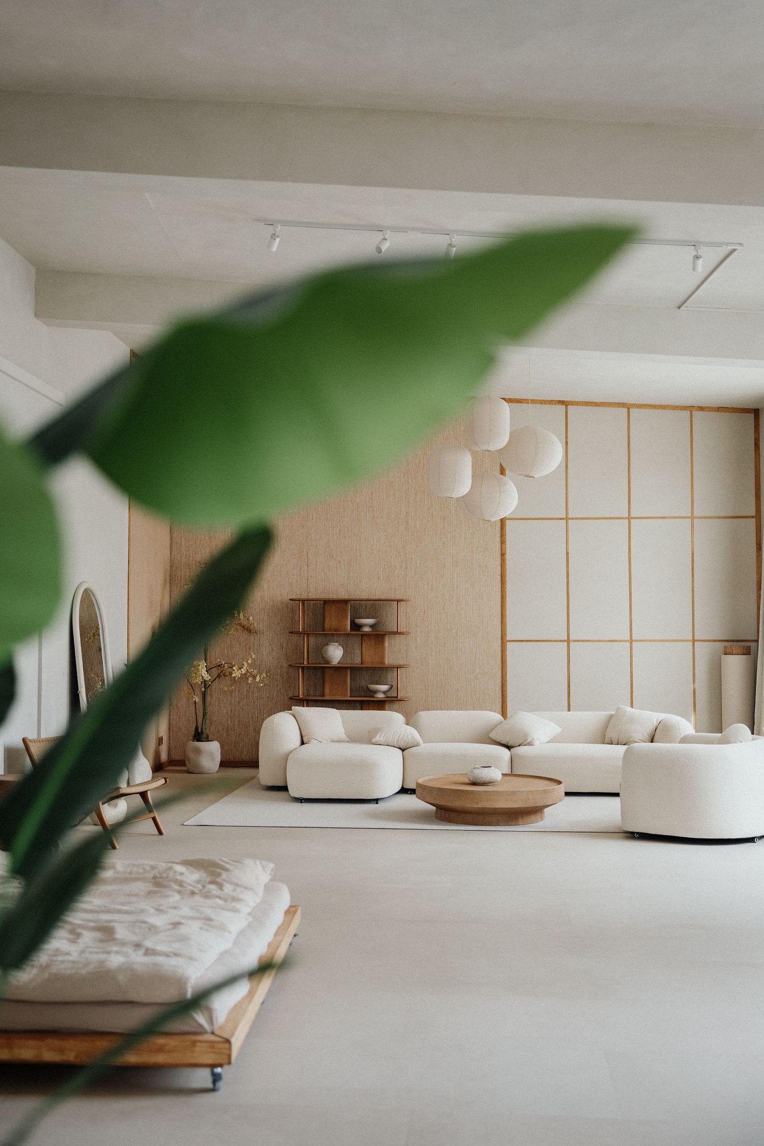 Minimalistisches japanisch inspiriertes Wohnzimmer mit weißen Sofas, Holzdetails & Pflanzen in hellem Raum – Business Shooting Frankfurt