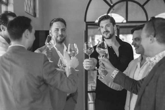 Gruppe von Gästen stößt mit Weingläsern in elegantem Innenraum an – festlich heiraten im Morrhof.