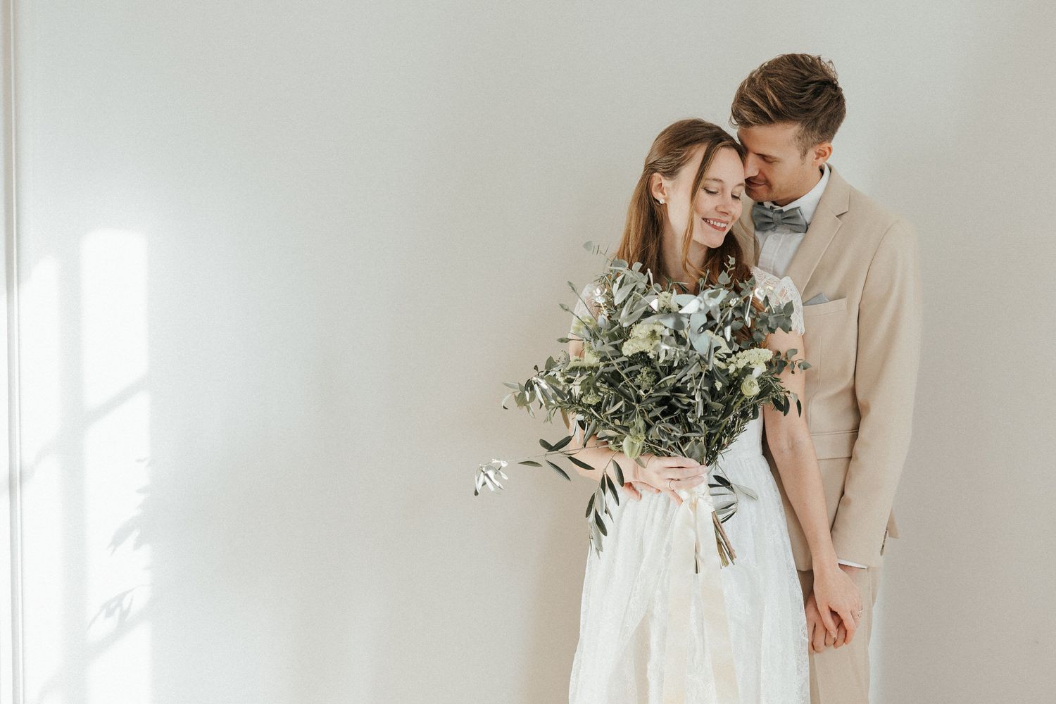 Intimate couple portrait session in bright minimalist white interior with natural lighting.