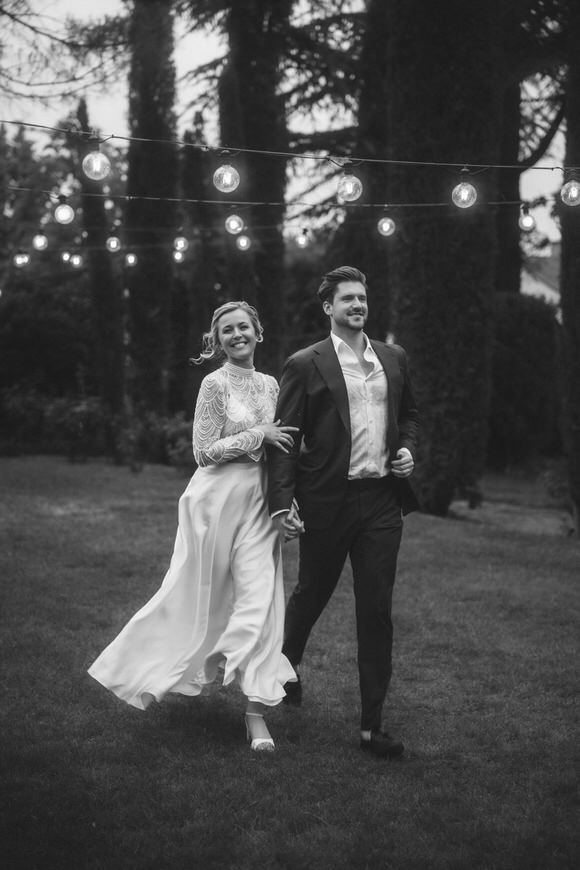 Paar tanzt glücklich unter funkelnden Lichtern zwischen den Bäumen bei Dämmerung – unvergesslich heiraten im Morrhof.