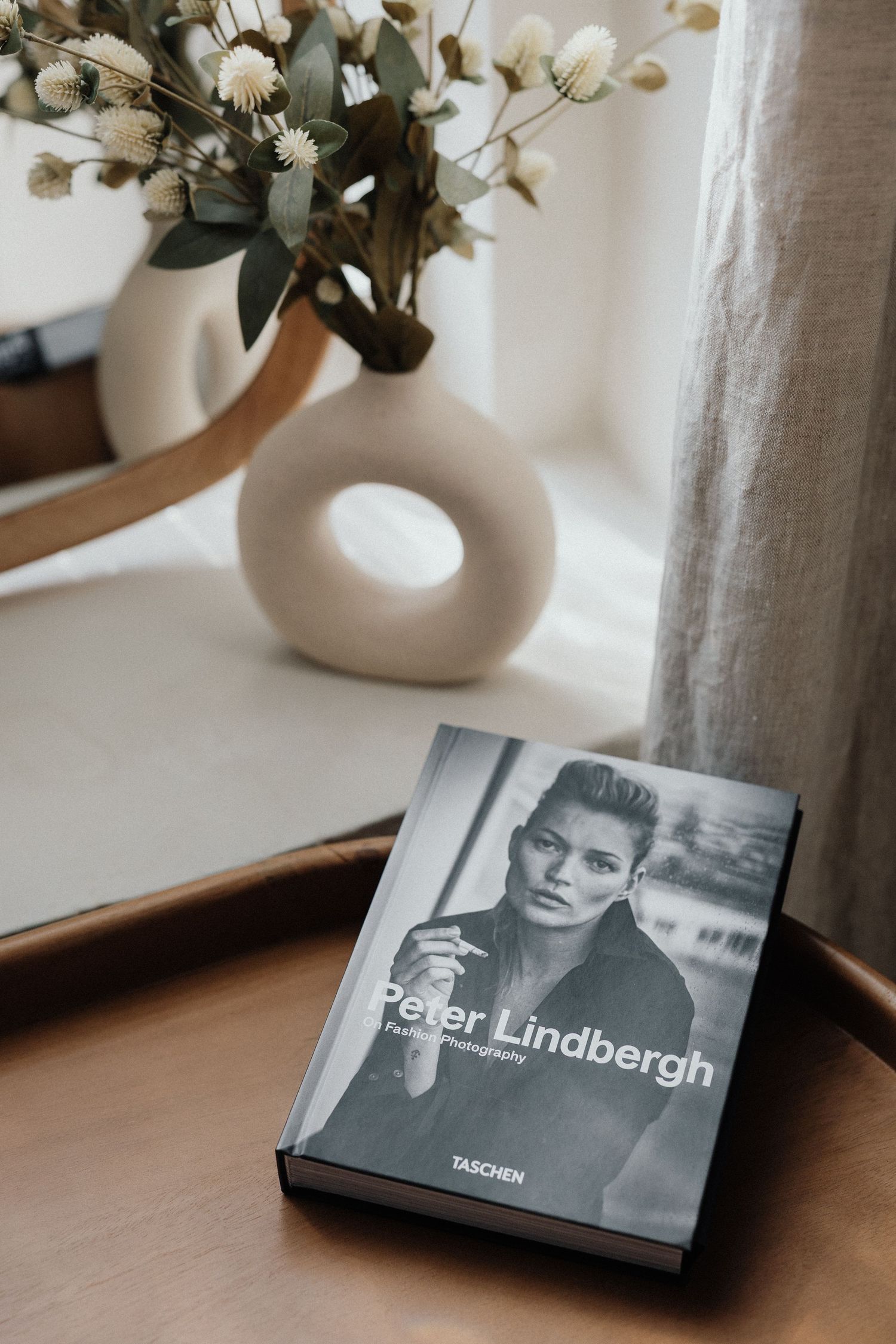 Peter Lindbergh Fotobuch auf Holzfläche neben modernem weißen Vase mit getrockneten Blumen – Business Shooting Frankfurt