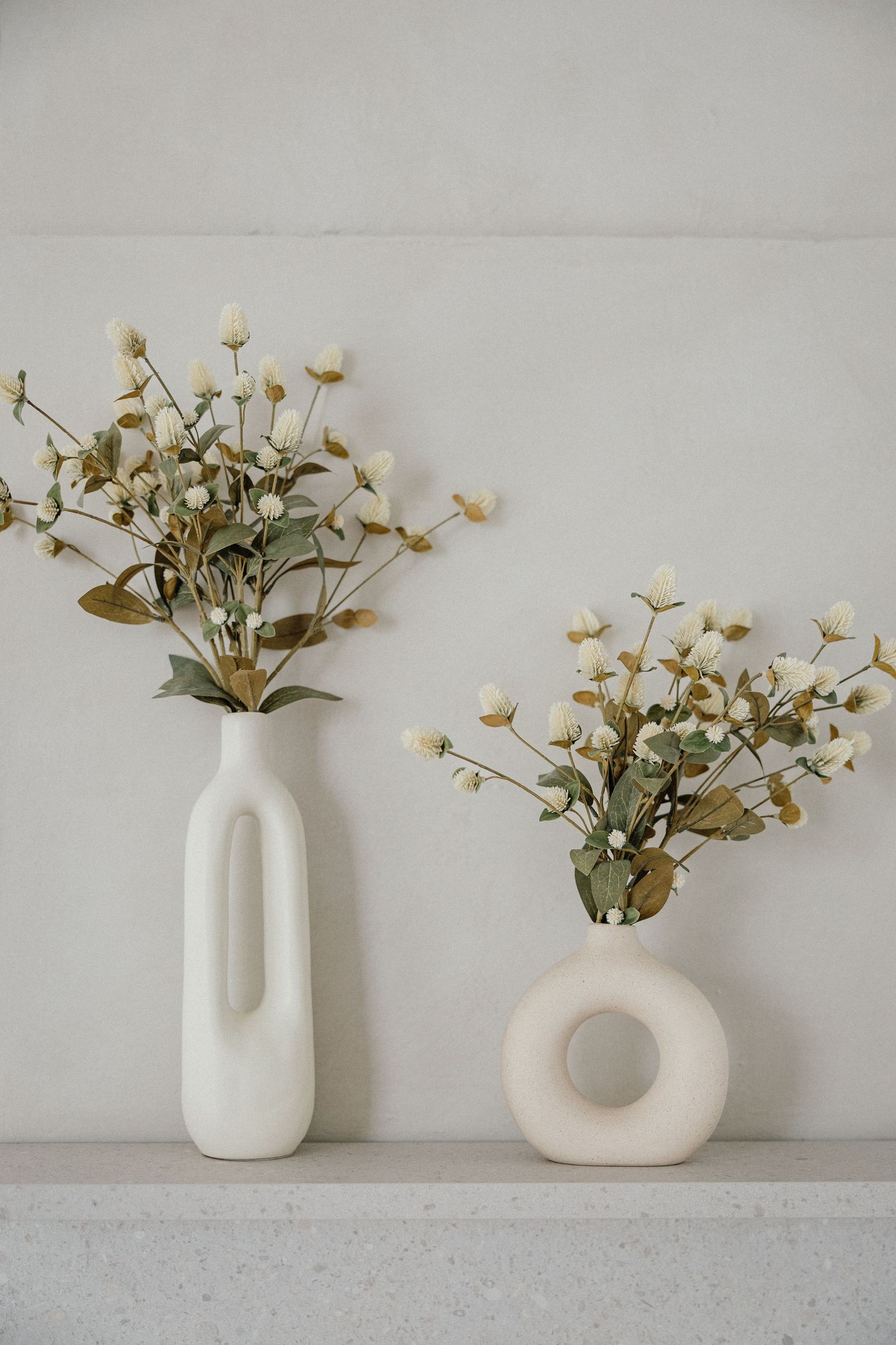 Minimalistische weiße Keramikvasen mit zarten Blumen auf hellgrauer Oberfläche modern arrangiert – Business Shooting Frankfurt