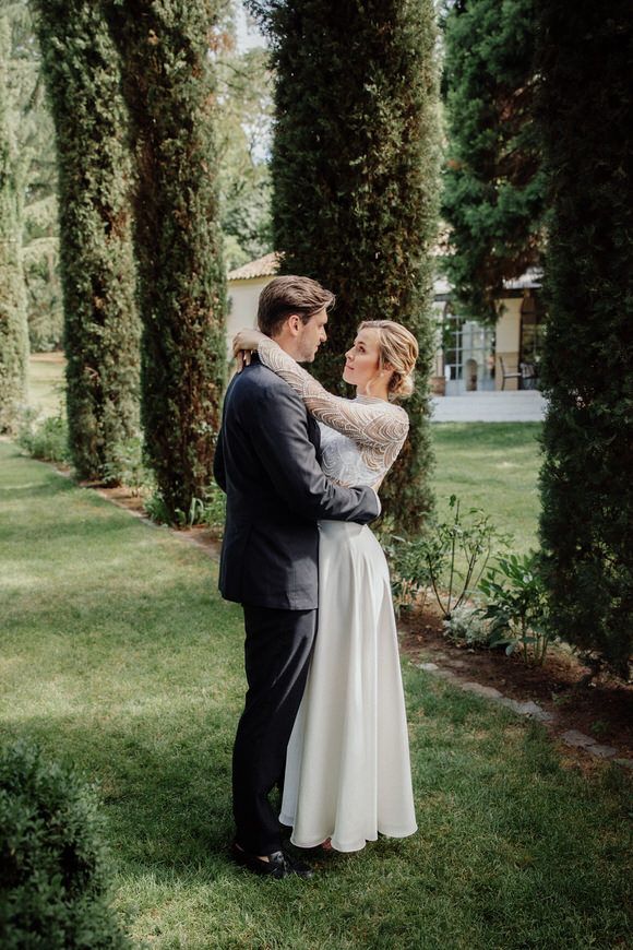 Hochzeitspaar umarmt sich zwischen hohen Zypressen im Garten – pure Romantik beim heiraten im Morrhof.