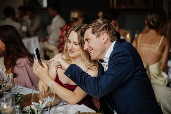 Intimes Hochzeitsdinner mit Gästen, die bei Kerzenschein gemeinsam lachen – unvergesslich heiraten im Morrhof.