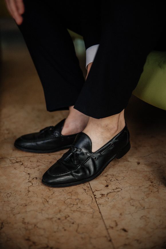 Schwarze Lederslipper liegen auf einem strukturierten Steinboden – elegante Details beim heiraten im Morrhof.