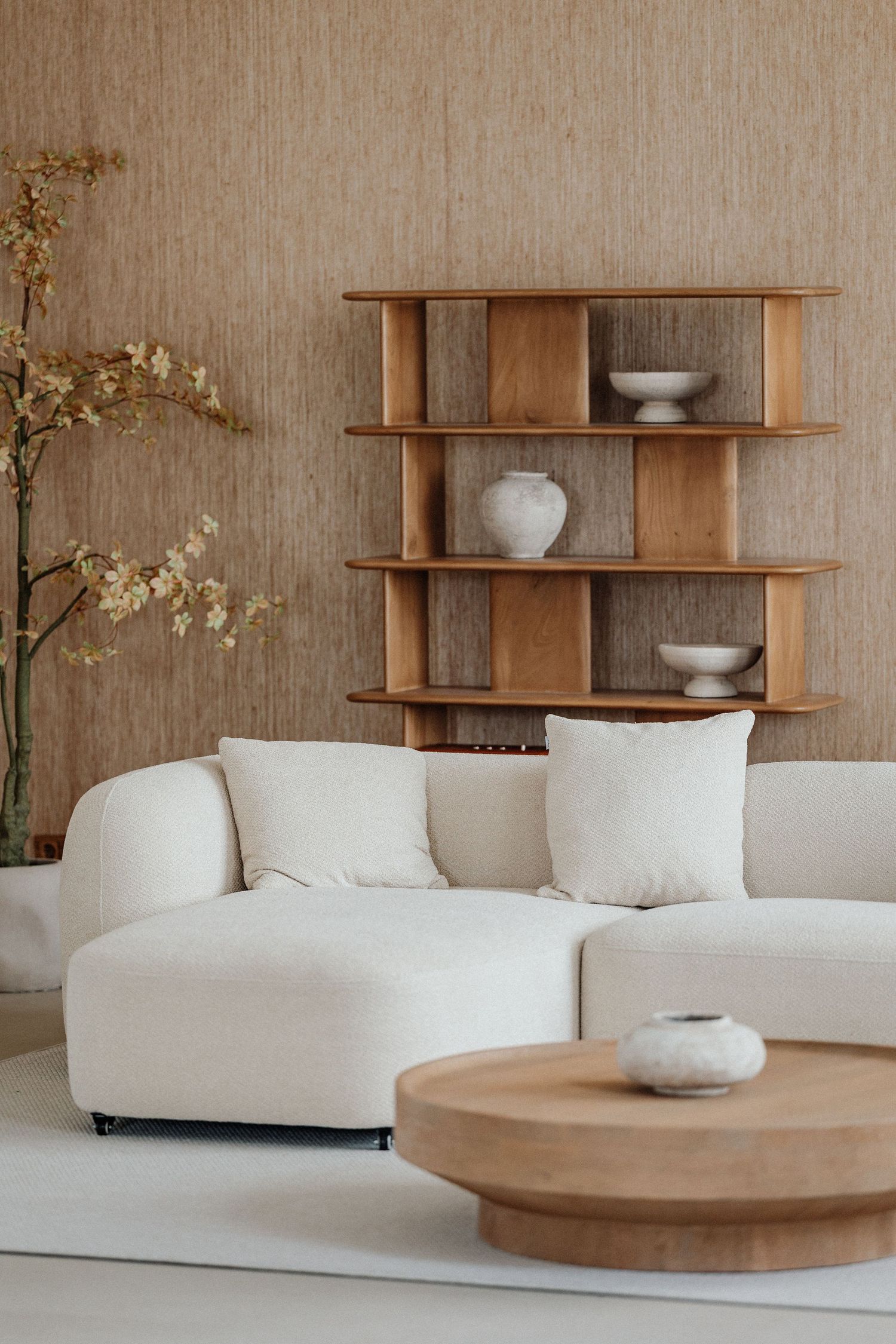 Modernes minimalistisches Wohnzimmer mit rundem weißen Sofa, Holzregalen & runden Couchtisch in neutralen Tönen – Business Shooting FFM