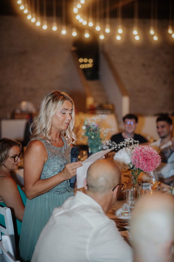 Hochzeitsfotograf Boudier & Koeller – Gäste in türkisfarbenen Brautjungfernkleidern an Tischen unter Lichterketten.