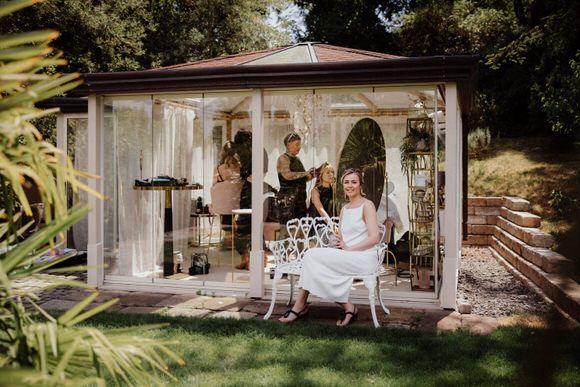 Weißer Gartenpavillon mit eleganten Sitzplätzen, umgeben von üppigem Grün – romantische Kulisse zum heiraten im Morrhof.