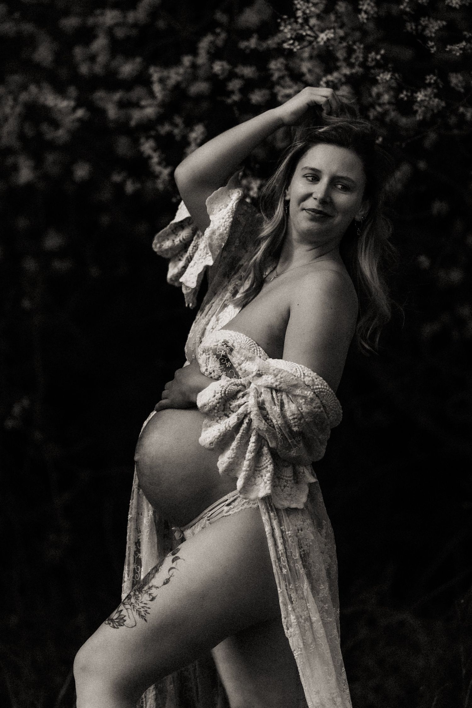 Black and white artistic maternity photos showing silhouetted pregnant figure in lace against dark background.