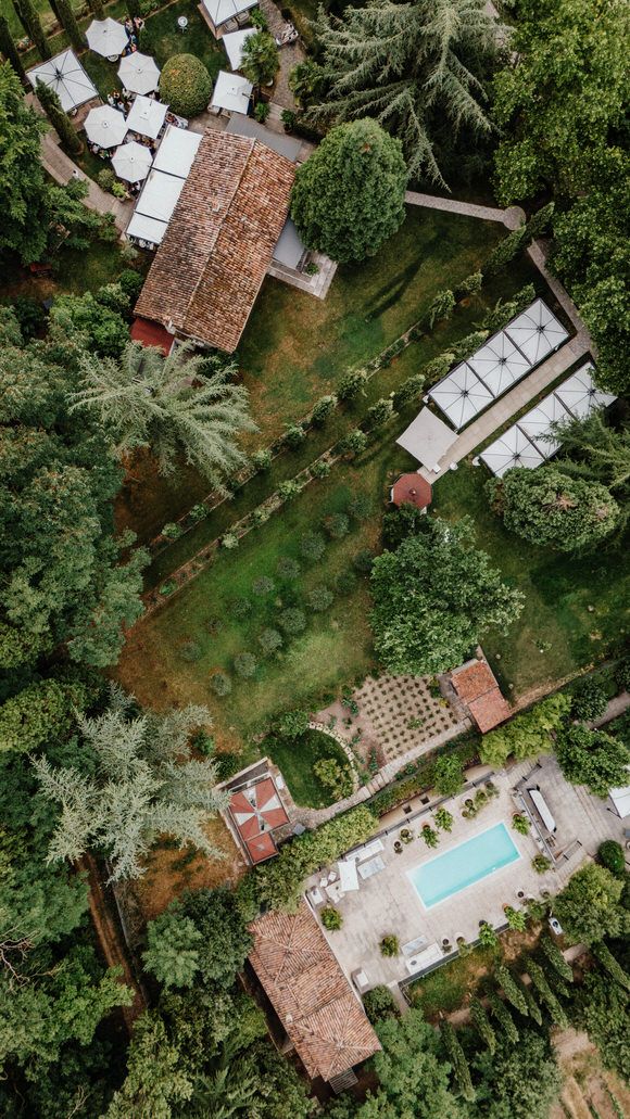 Drohnenaufnahme einer Villa mit Pool, umgeben von üppigen Gärten und weißen Zelten – die perfekte Kulisse zum heiraten im Morrhof.
