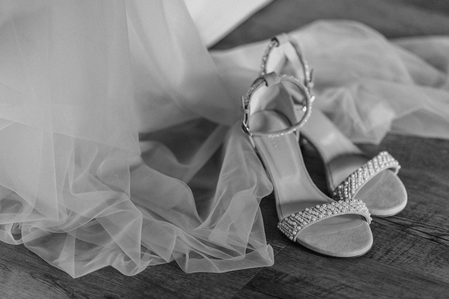 A delicate white wedding veil lies draped across a wooden surface with soft natural lighting.