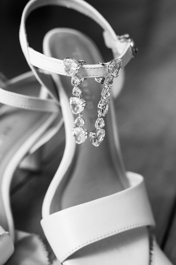 Elegant bridal shoes with crystal embellishments shown in black and white photography.