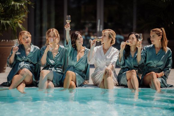Brautjungfern in türkisfarbenen Morgenmänteln entspannen am Pool vor der Hochzeit – stilvolle Vorbereitung beim heiraten im Morrhof.