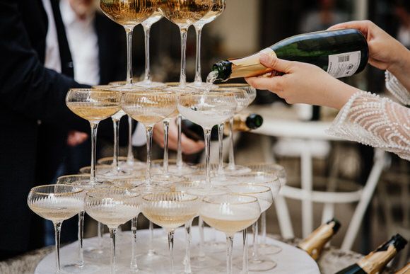 Champagner fließt in gestapelte Kristallgläser bei einer festlichen Outdoor-Feier – luxuriös heiraten im Morrhof.