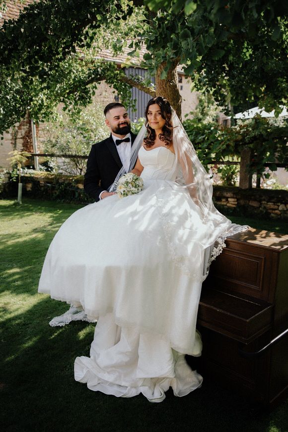Romantic wedding couple dancing and twirling in a garden setting with a vintage piano in the background.