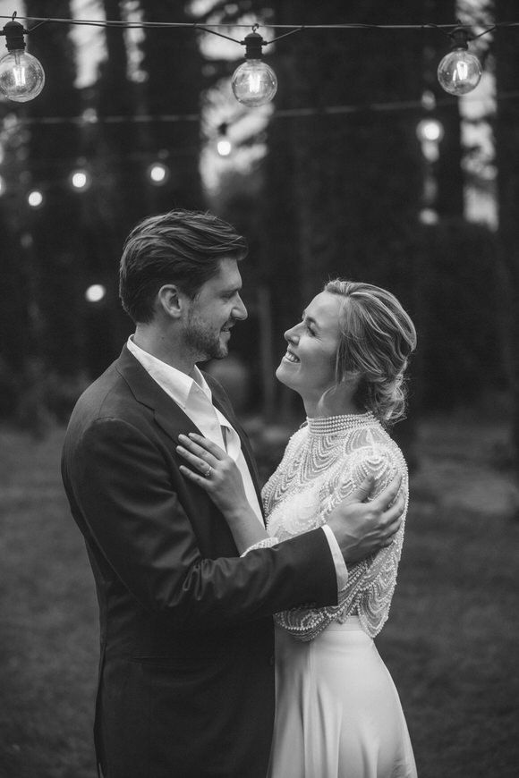 Romantisches Schwarz-Weiß-Foto eines tanzenden Paares unter Lichterketten – emotionale Erinnerungen beim heiraten im Morrhof.