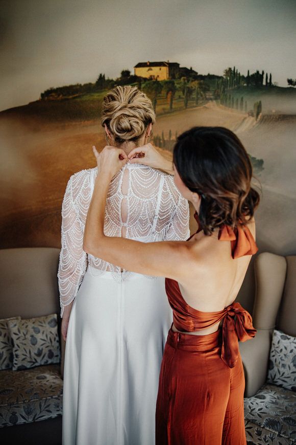 Detailaufnahme eines weißen Spitzenkleides neben einem rostroten Brautjungfernkleid – liebevolle Vorbereitung beim heiraten im Morrhof.