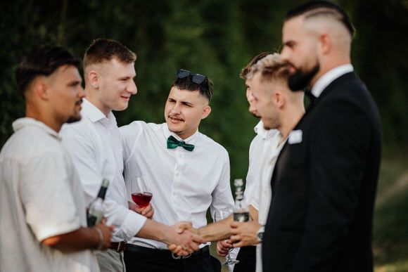 Hochzeitsfotograf Boudier & Koeller – Trauzeugen teilen Drinks und lachen gemeinsam während Outdoor-Hochzeitsfeier.