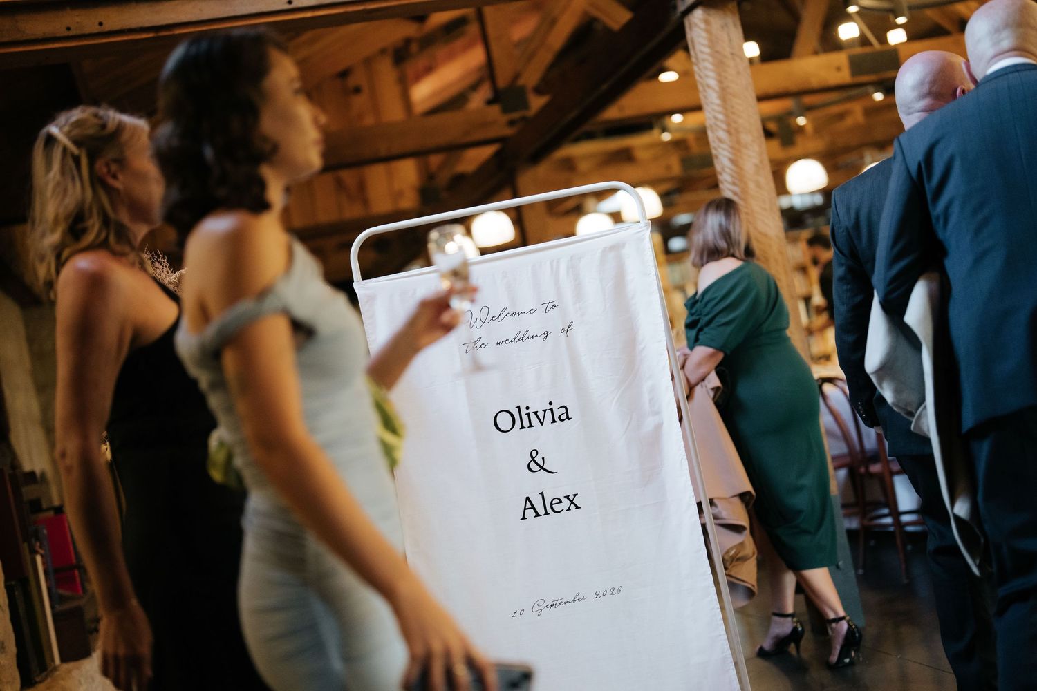 Wedding reception sign displaying Olivia and Alex names in elegant typography inside a rustic barn venue.