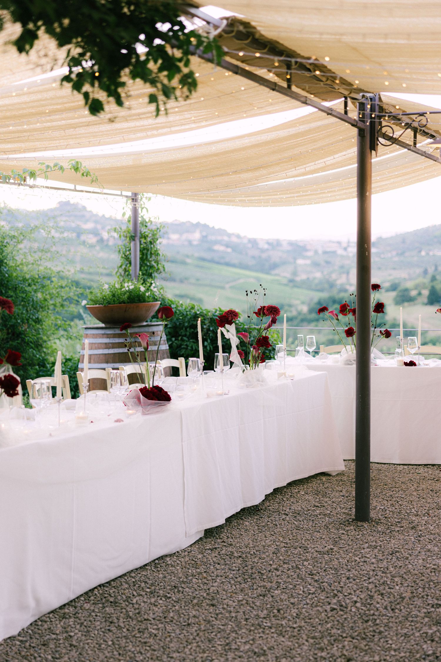Elegant outdoor wedding reception table setup with white linens and mountain views under a canvas canopy.