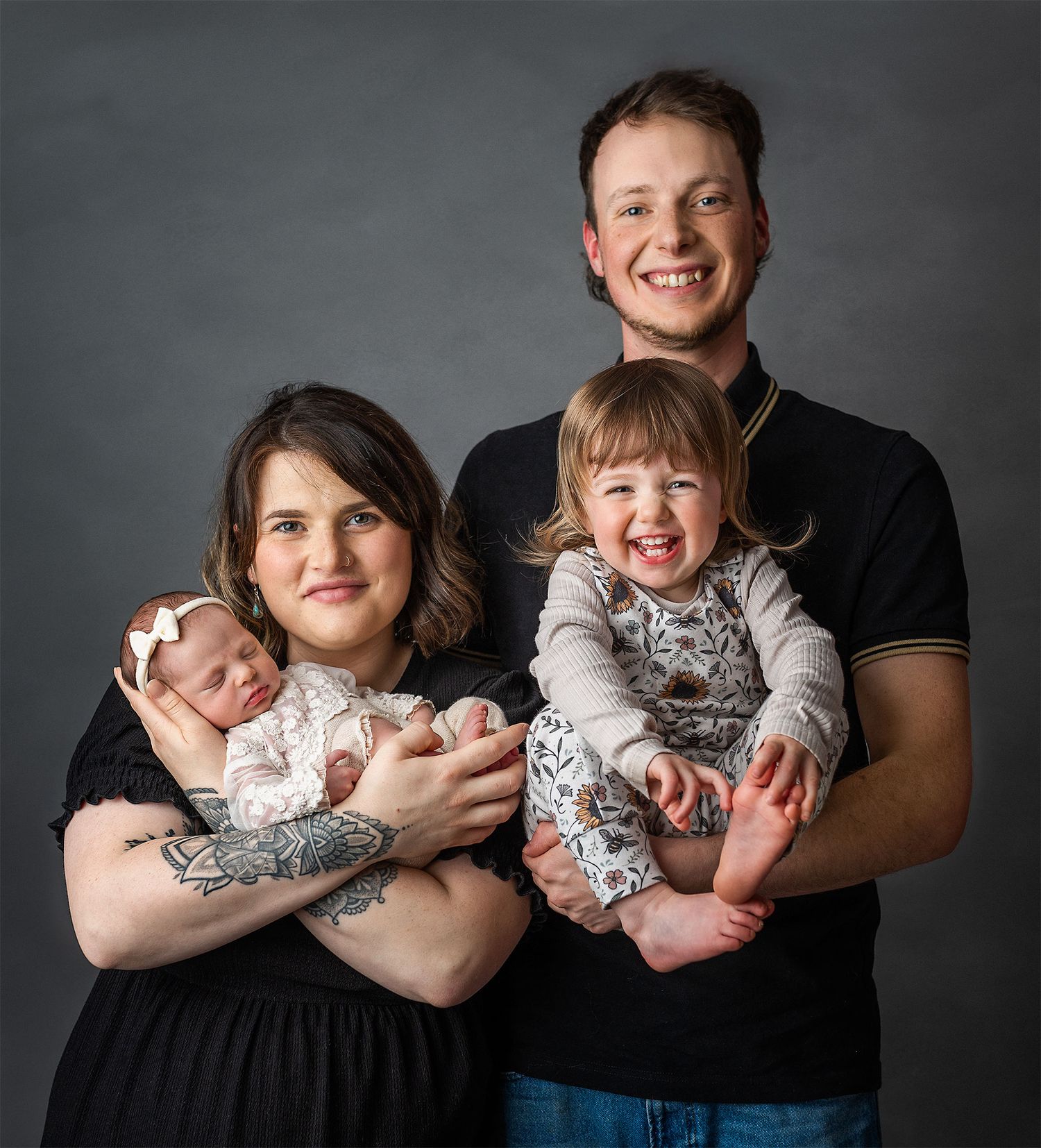 A family photo to be cherished for generations. Mum, dad and daughters posing for their first family shoot with baby.