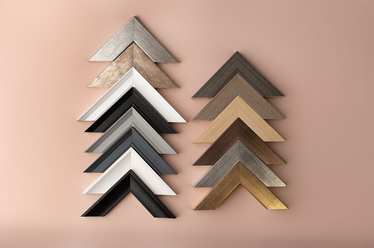 Minimalist geometric wall art featuring triangular shapes in black, white, and metallic tones arranged on a blush pink background.