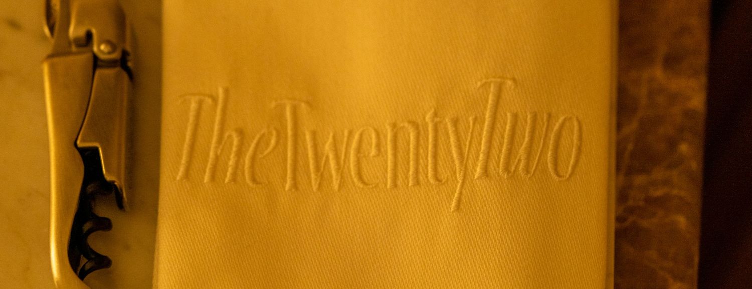 A close-up of an embossed gold menu or book cover reading The Twenty Two.