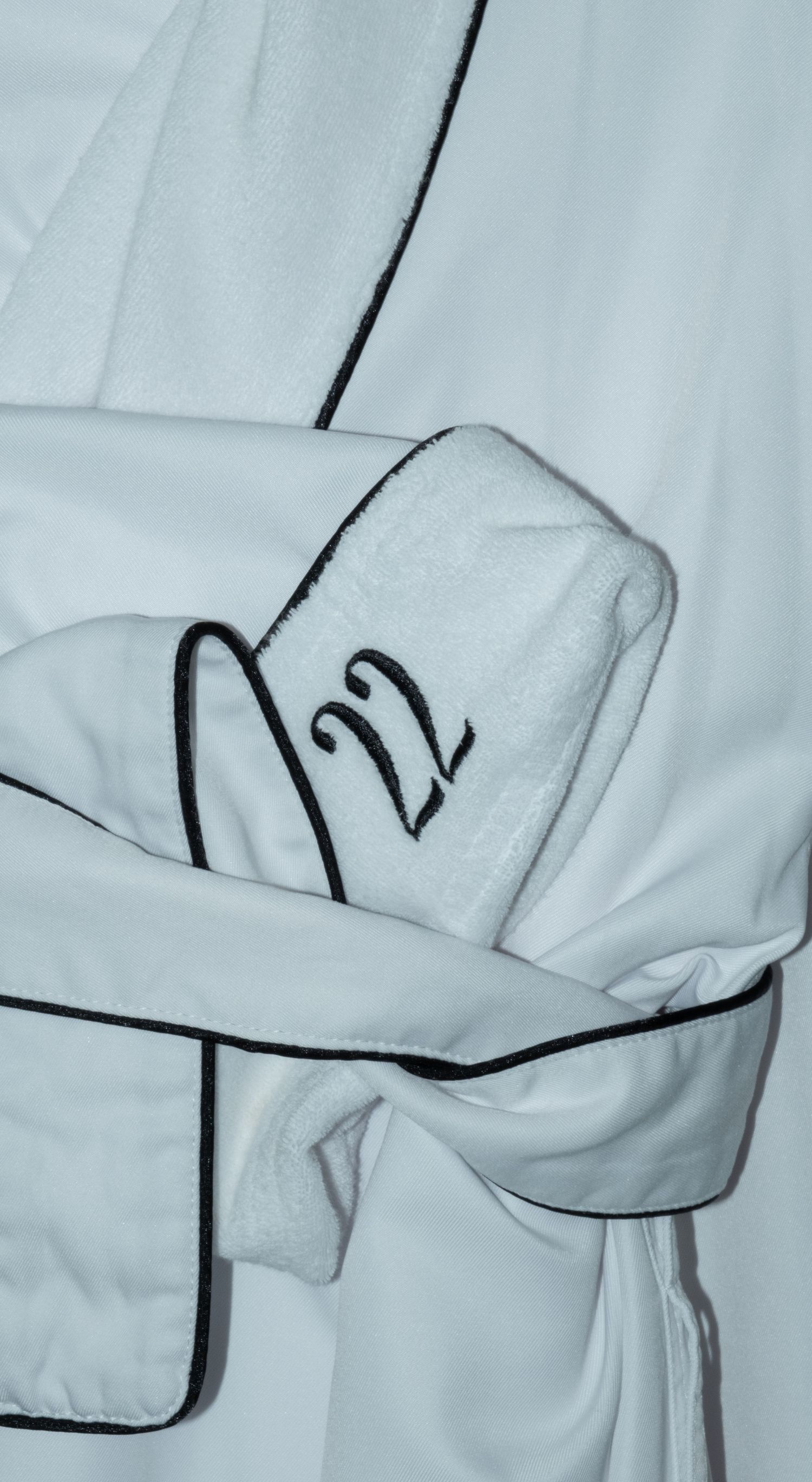 White luxury hotel bathrobe with black piping and embroidered number 22 on the sleeve.