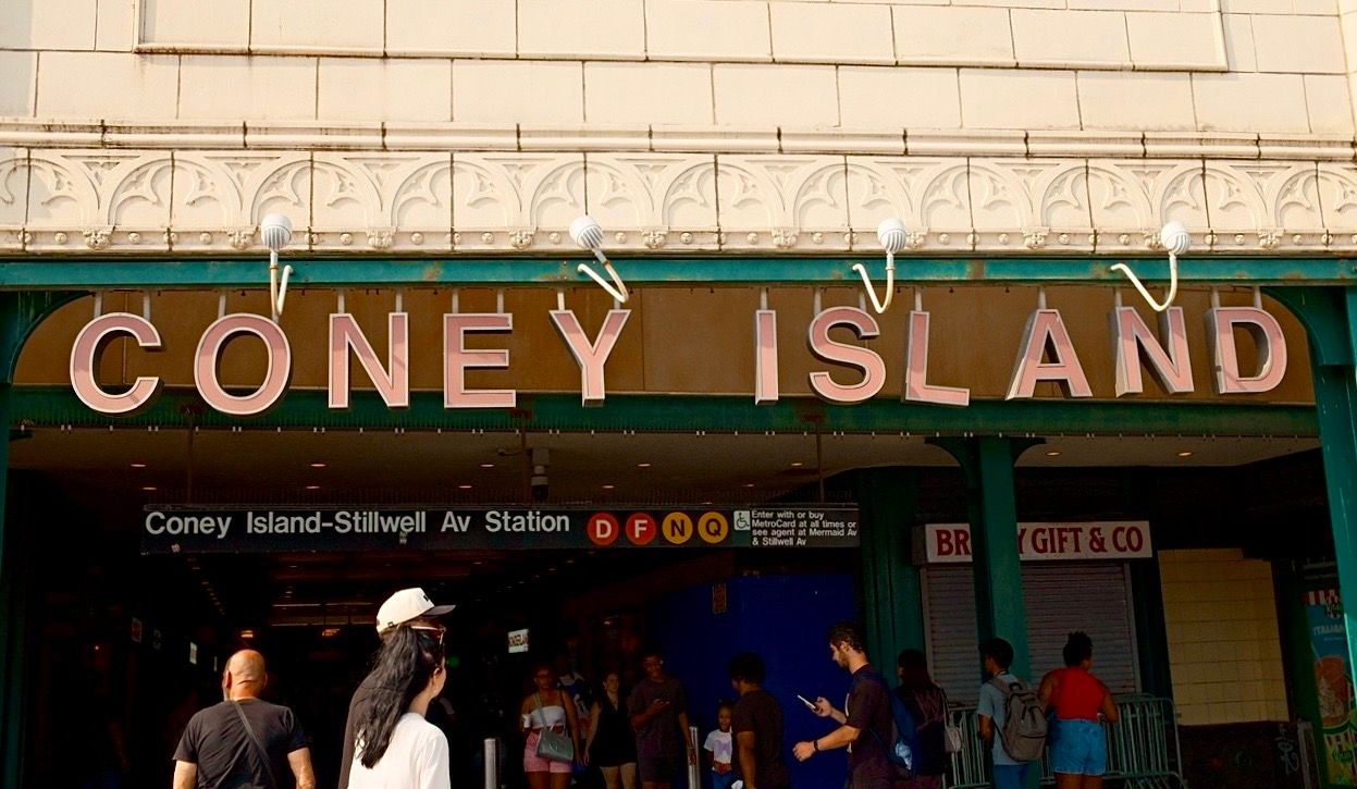 Coney Island-Stillwell Av Station entrance sign with colorful subway line indicators in Brooklyn, New York.