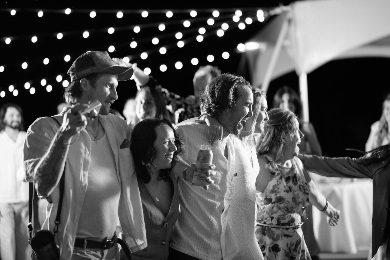 Guests dancing under twinkling string lights at an outdoor evening wedding reception.