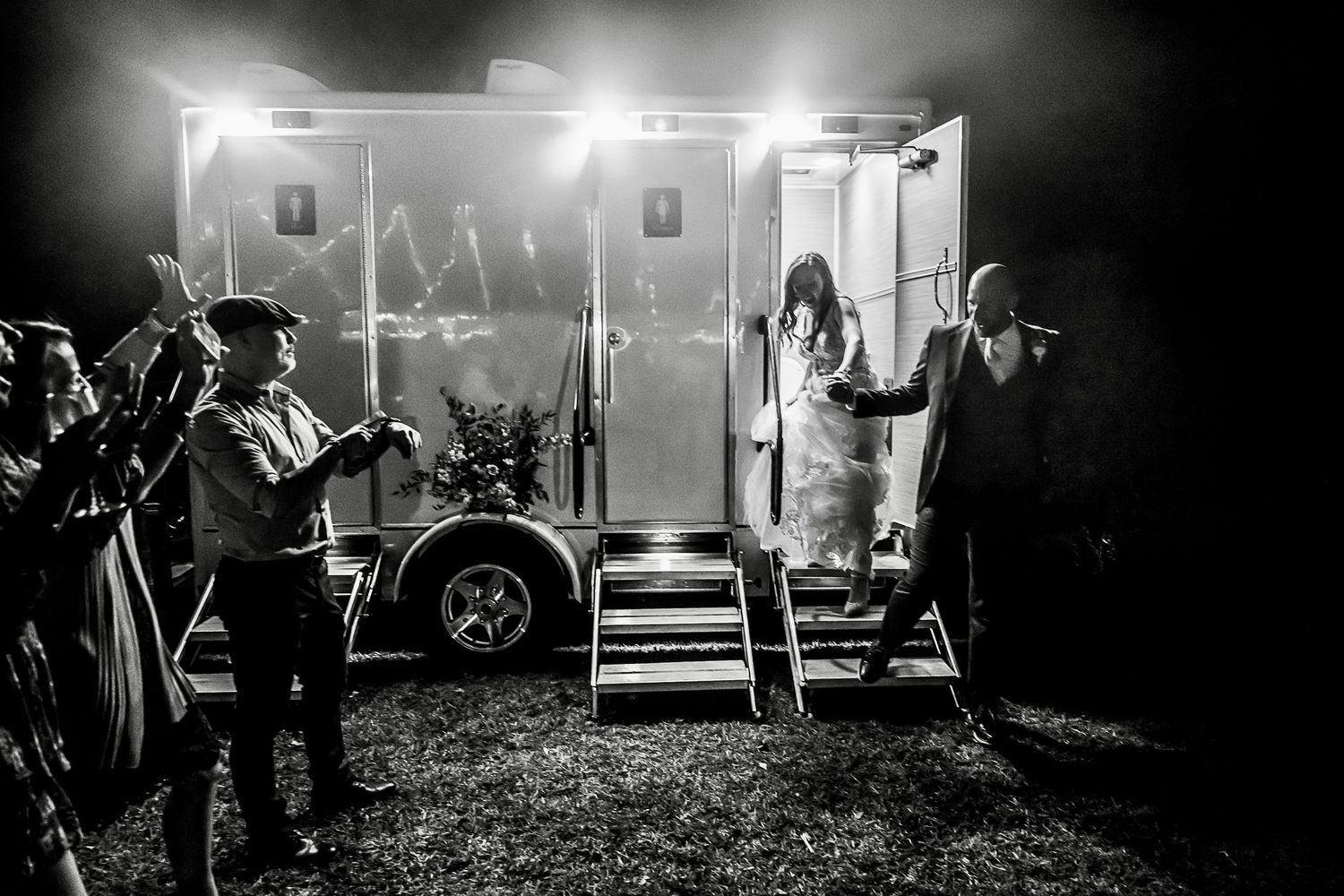 A dramatic black and white photo shows performers on stage with intense lighting and smoke effects during a nighttime show.