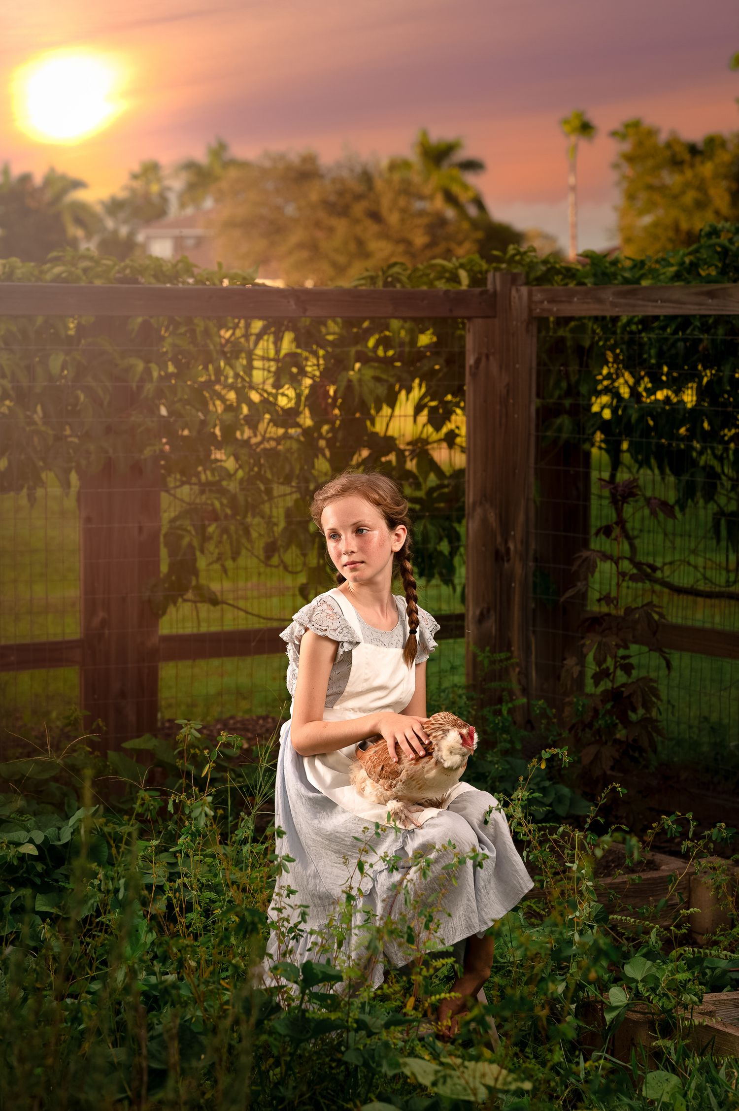 A dreamy sunset scene in a garden with a white dress visible among lush greenery and wooden fence posts.
