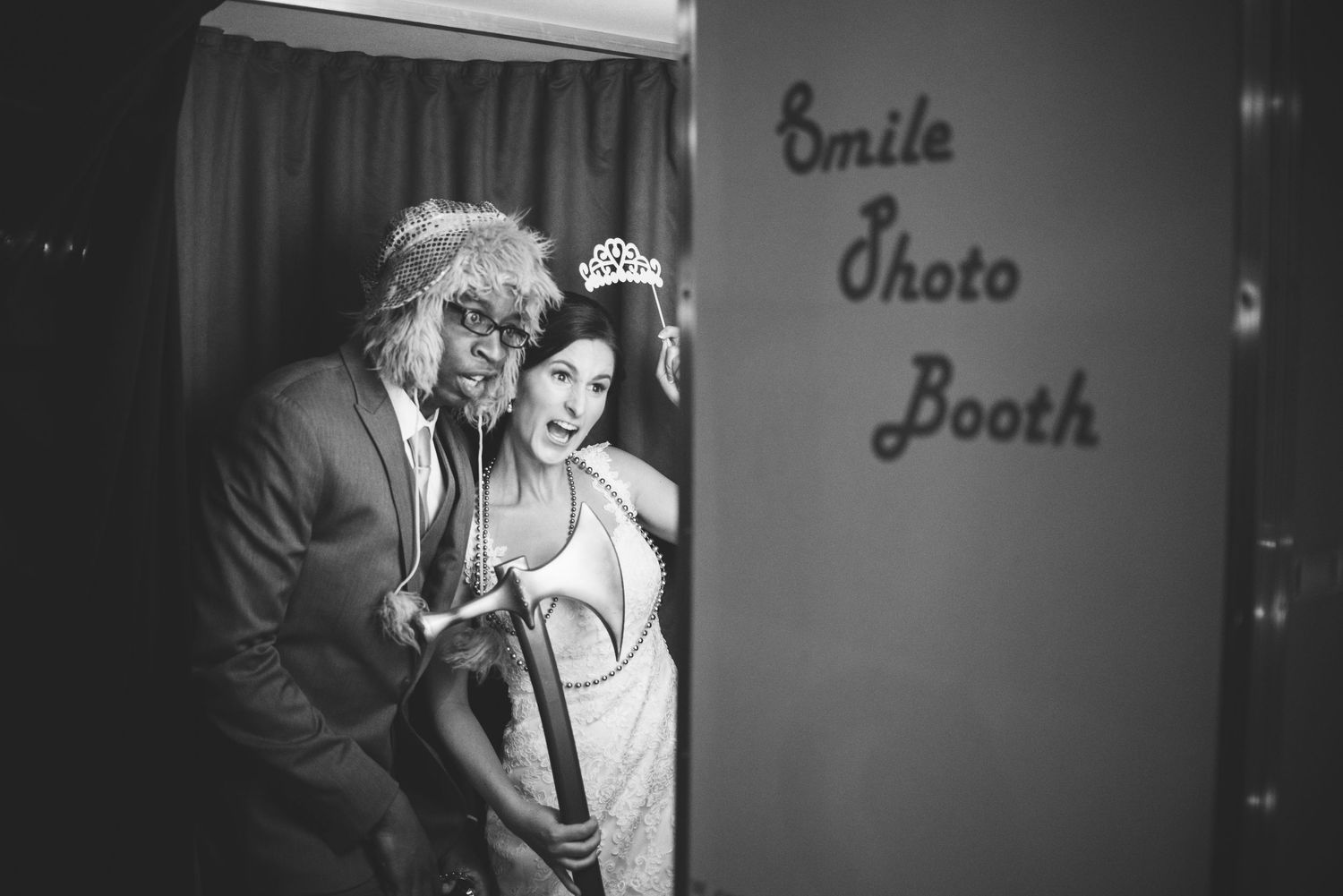 A black and white photo showing a playful moment at a wedding venue's photo booth.