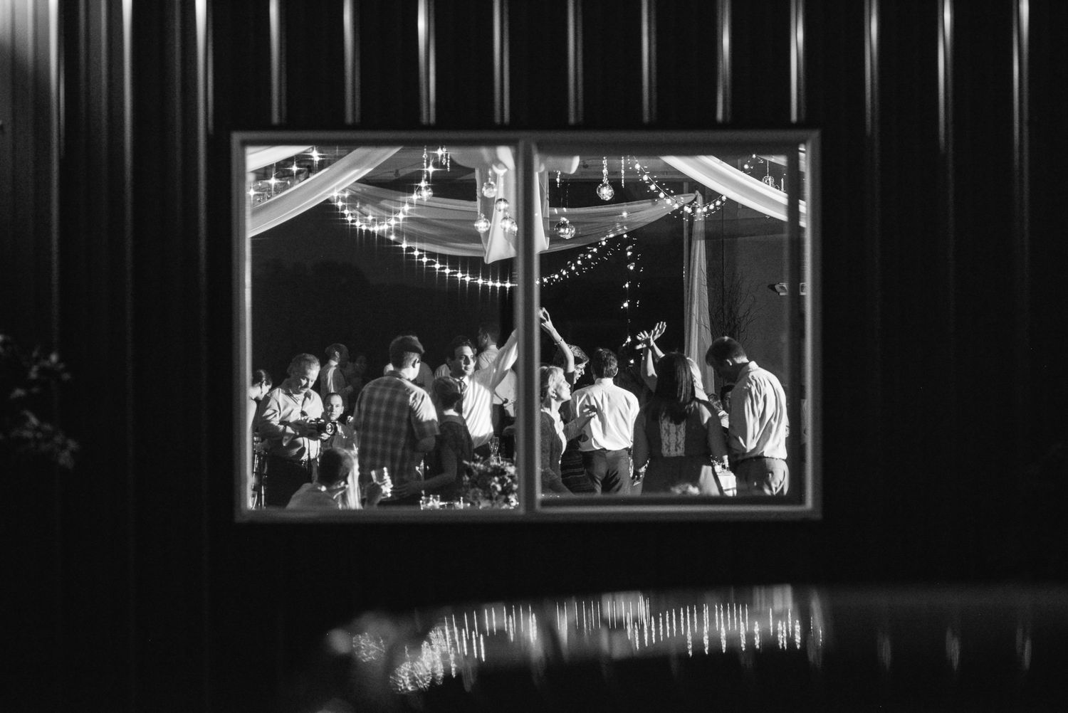 Black and white panoramic view of wedding reception venue with dramatic lighting.