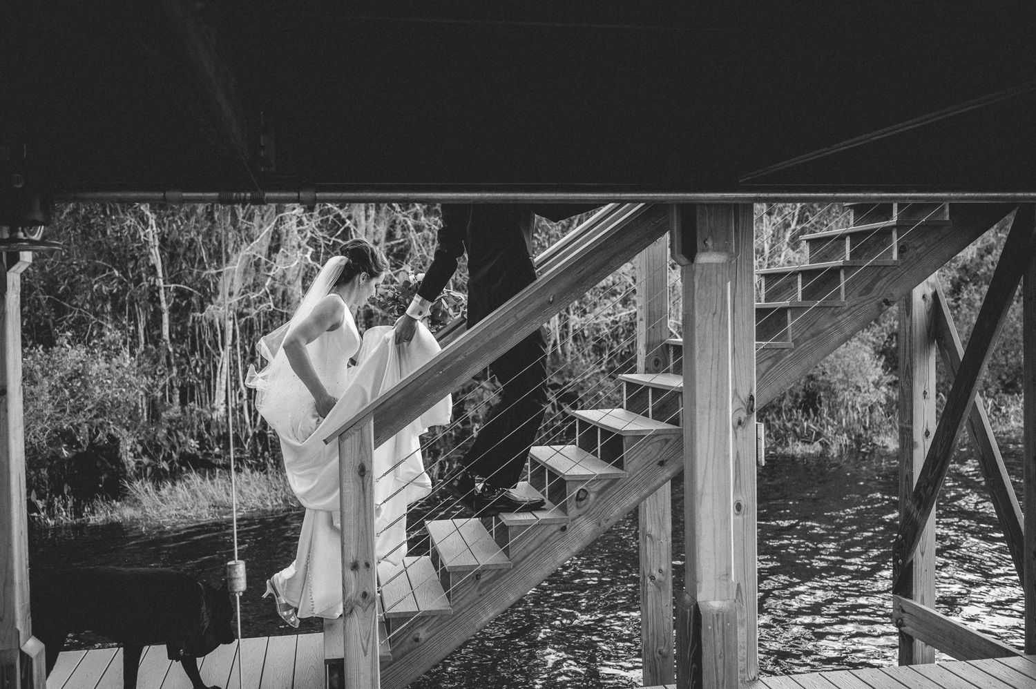 A romantic black and white photograph of a couple sharing a tender moment on wooden stairs outdoors.